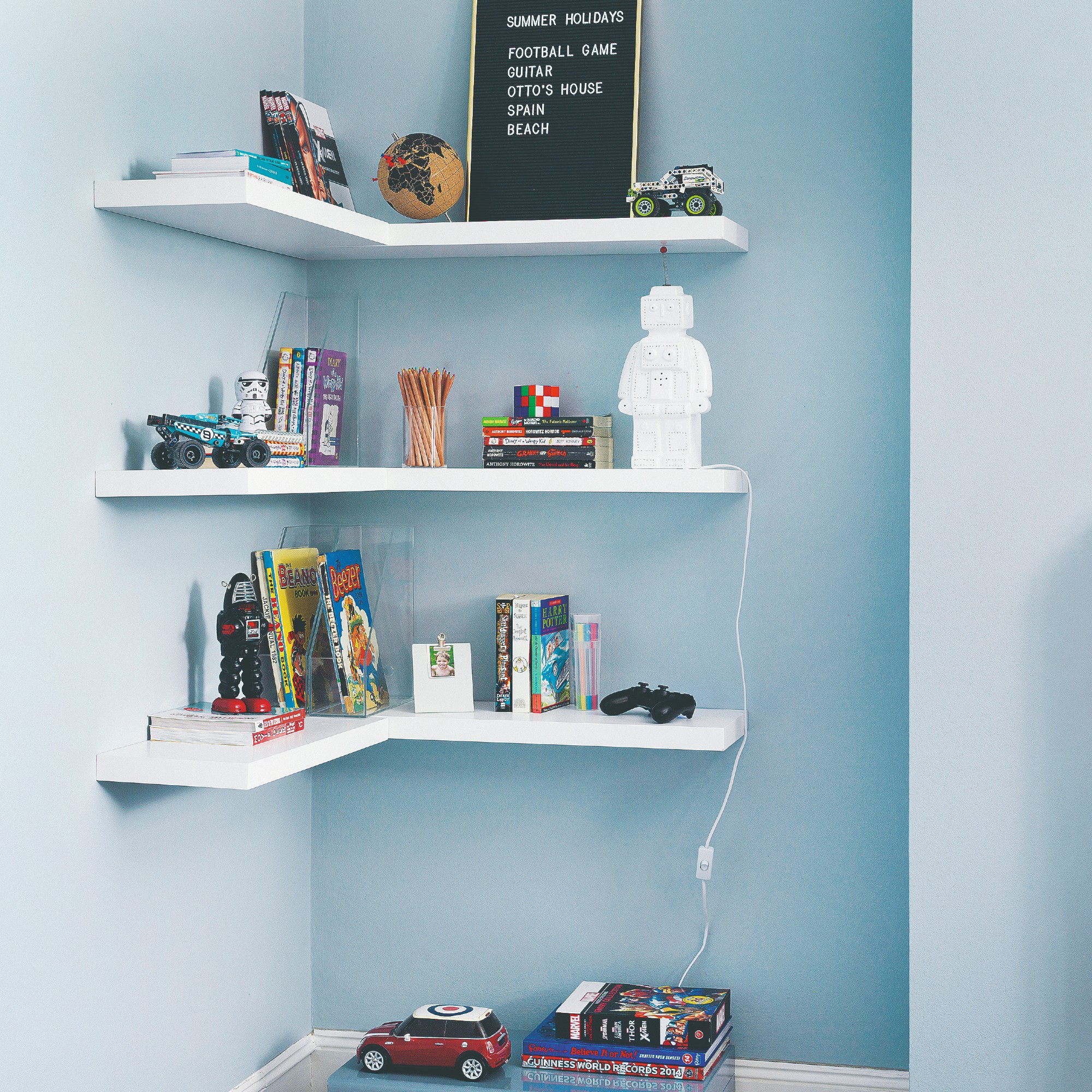 A light blue-painted teenager's bedroom with floating shelves vertically arranged displaying the child's belongings
