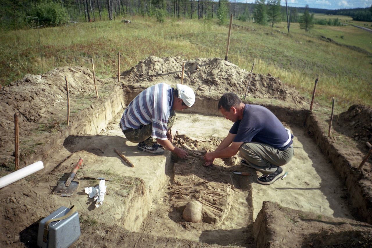 two men work at an excavation site uncovering a skeleton