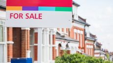 A 'For Sale' sign is displayed outside a terraced house