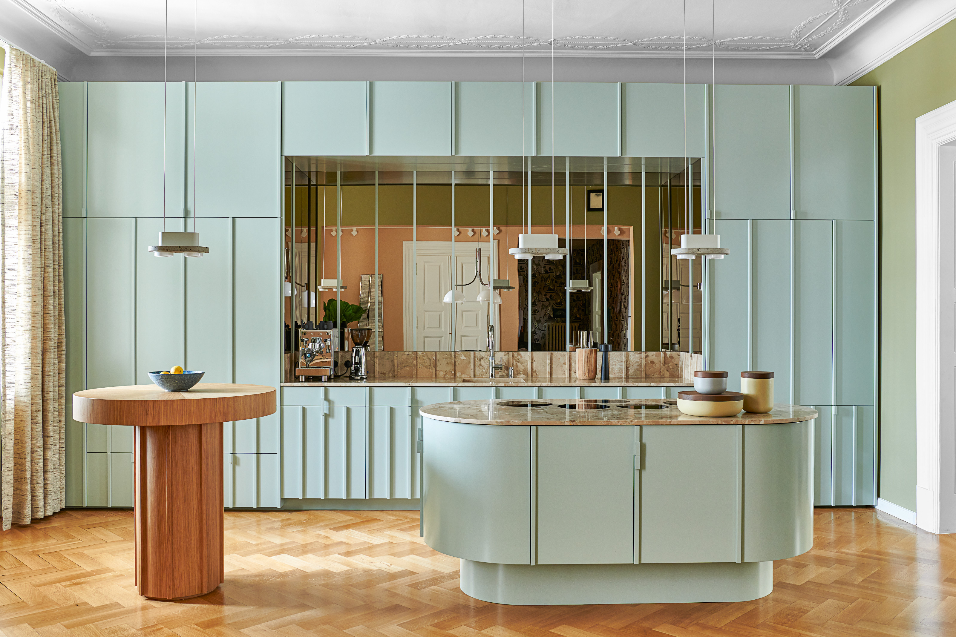 Blue panelled kitchen with rounded island and mirrored splashback