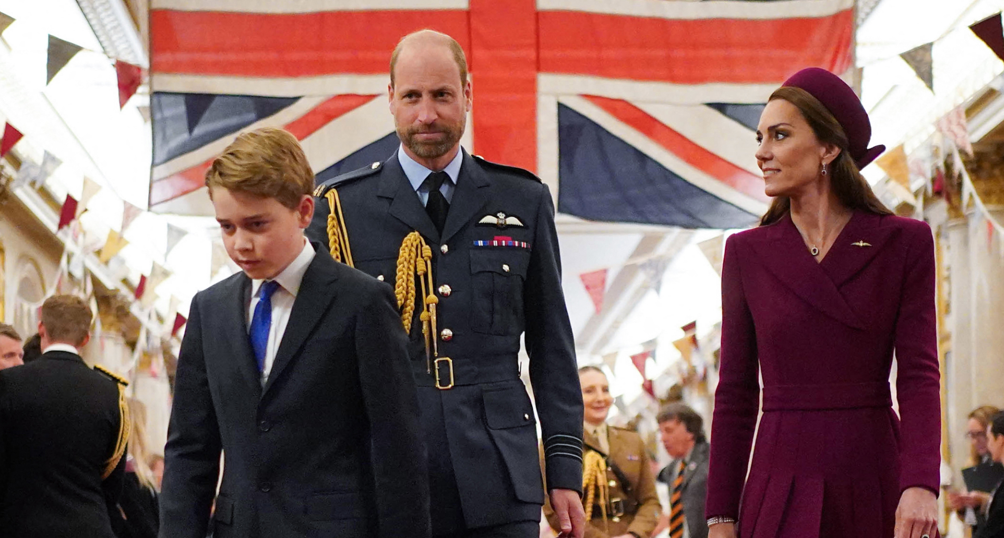 Prince George walking in front of Prince William and Prince Kate and a Union Jack flag