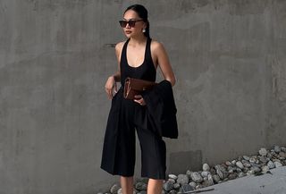 rich looking summer finds shown on a woman wearing a black scoop neck tank top with bermuda shorts, a brown clutch, and silver earrings