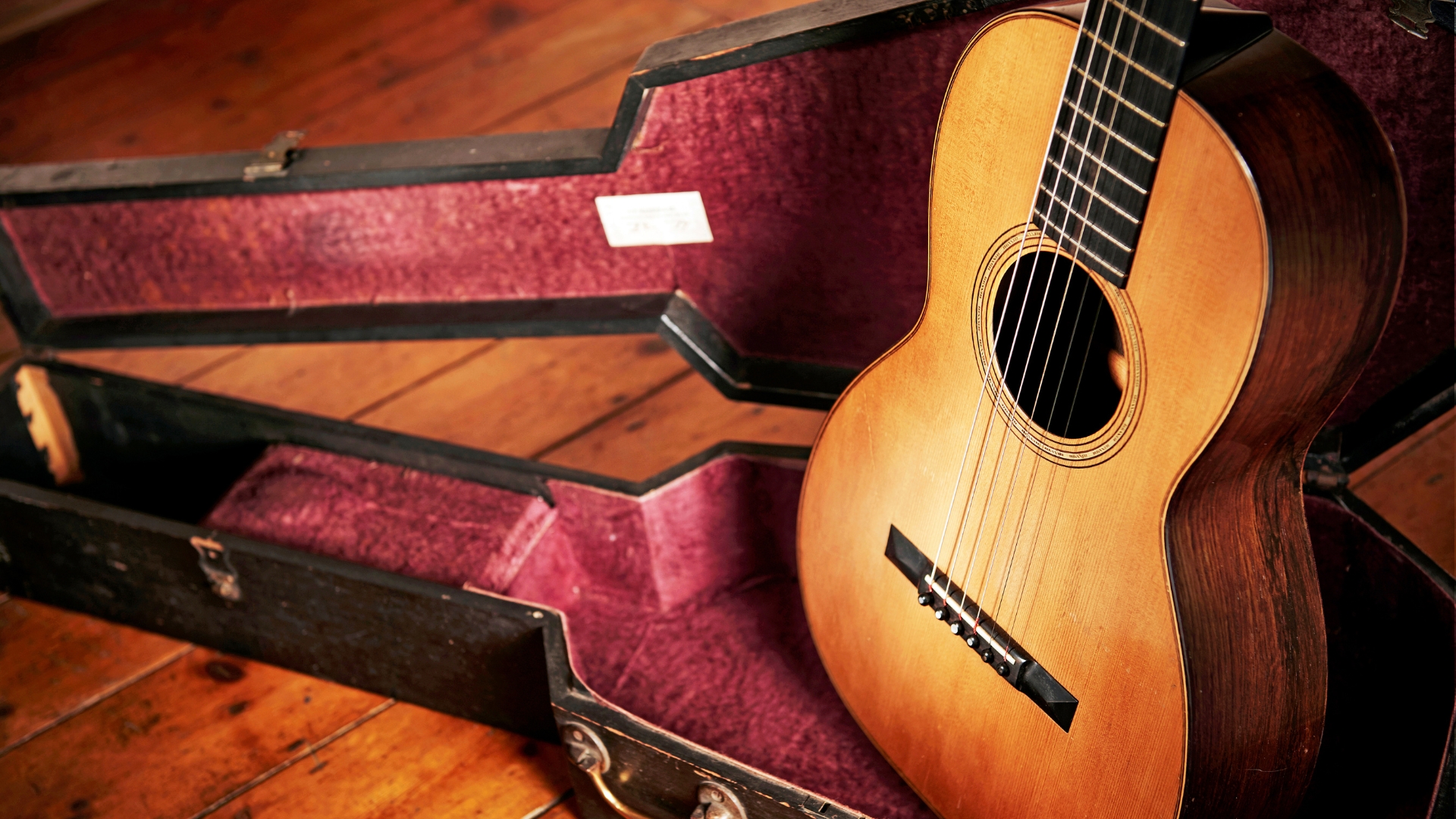 An acoustic guitar sitting in a hard case