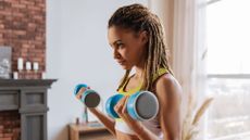 A woman performing a home workout with dumbbells