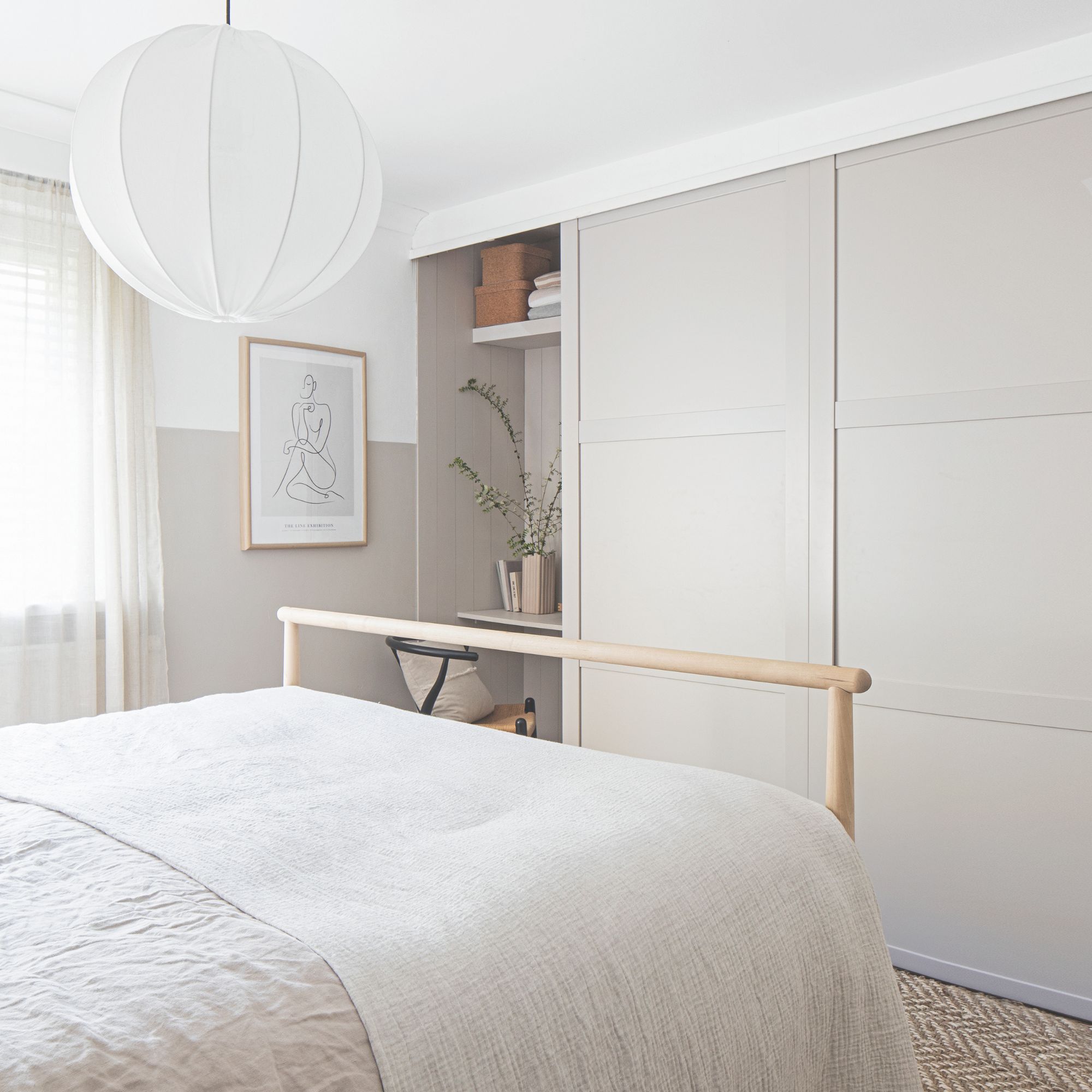 White bedroom with white bedding, cream and white walls, and fitted wardrobes