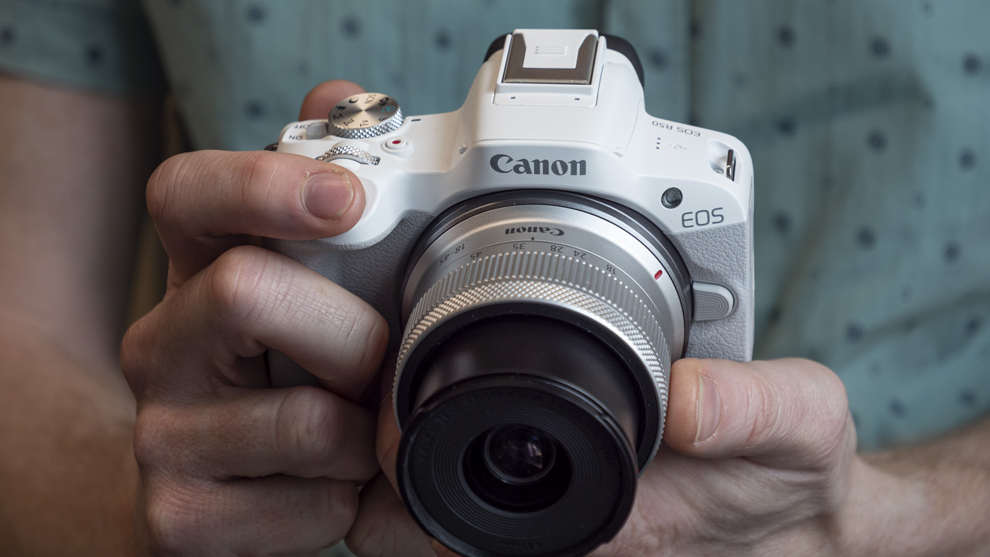 Canon EOS R50 in the hand focused on 18-45mm lens