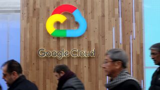 Google Cloud logo on a wooden background with pedestrians walking on a street in front of it