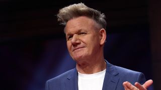 Gordon Ramsay in blue jacket and white shirt hosting MasterChef Season 16