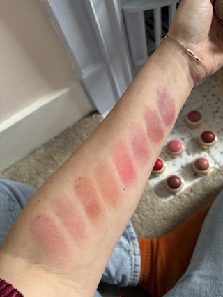 Mica Ricketts showing swatches of Merit Beauty Flush Balm on her arm