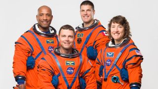 four astronauts wearing orange space suits