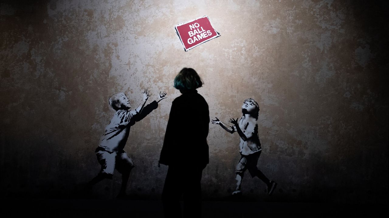 Banksy&#039;s 2009 mural No Ball Games, with a passer-by in the foreground