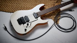 A Harley Benton Fusion IV HH electric guitar lies on a white floor with a rug and guitar cable nearby