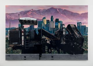 Sayre Gomez photograph on gallery wall, showing industrial equipment against city skyline and mountains beyond
