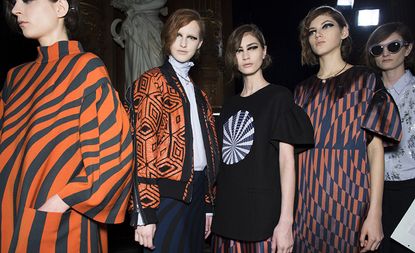 Female models stood in a line wearing black & orange clothing