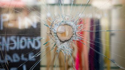 The window of a business has a bullet hole in it.