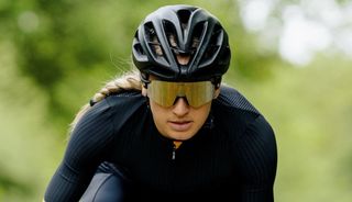 Woman cycles towards the camers whilst wearing SunGod Airas sunglasses