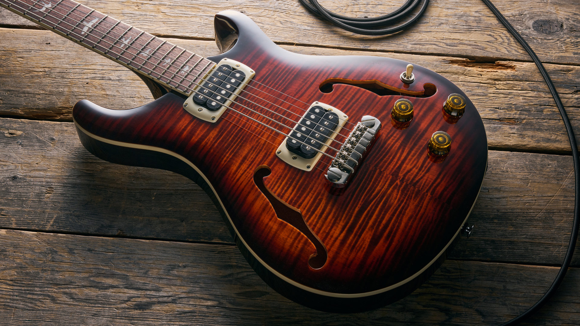 A PRS‍ SE⁢ Ed sheeran​ Hollowbody I ​Piezo Baritone guitar lying on a wooden floor