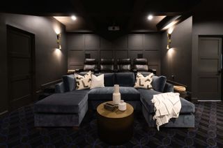 small media room with cinema seats, couch, dark walls, wall lights