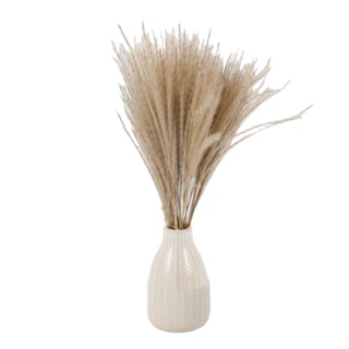 A bunch of pampas grass in a patterned white vase