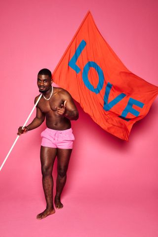 Dami Hope for Love Island 2022, holding up a red flag with Love written on it.