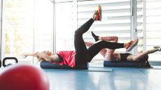 Two women performing dead bug on a foam roller