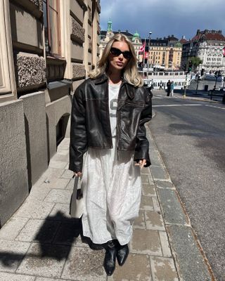 Elsa Hosk wearing a Helsa leather jacket, white skirt, and boots.