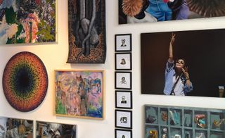A variety of different sized and types of paintings on a wall.