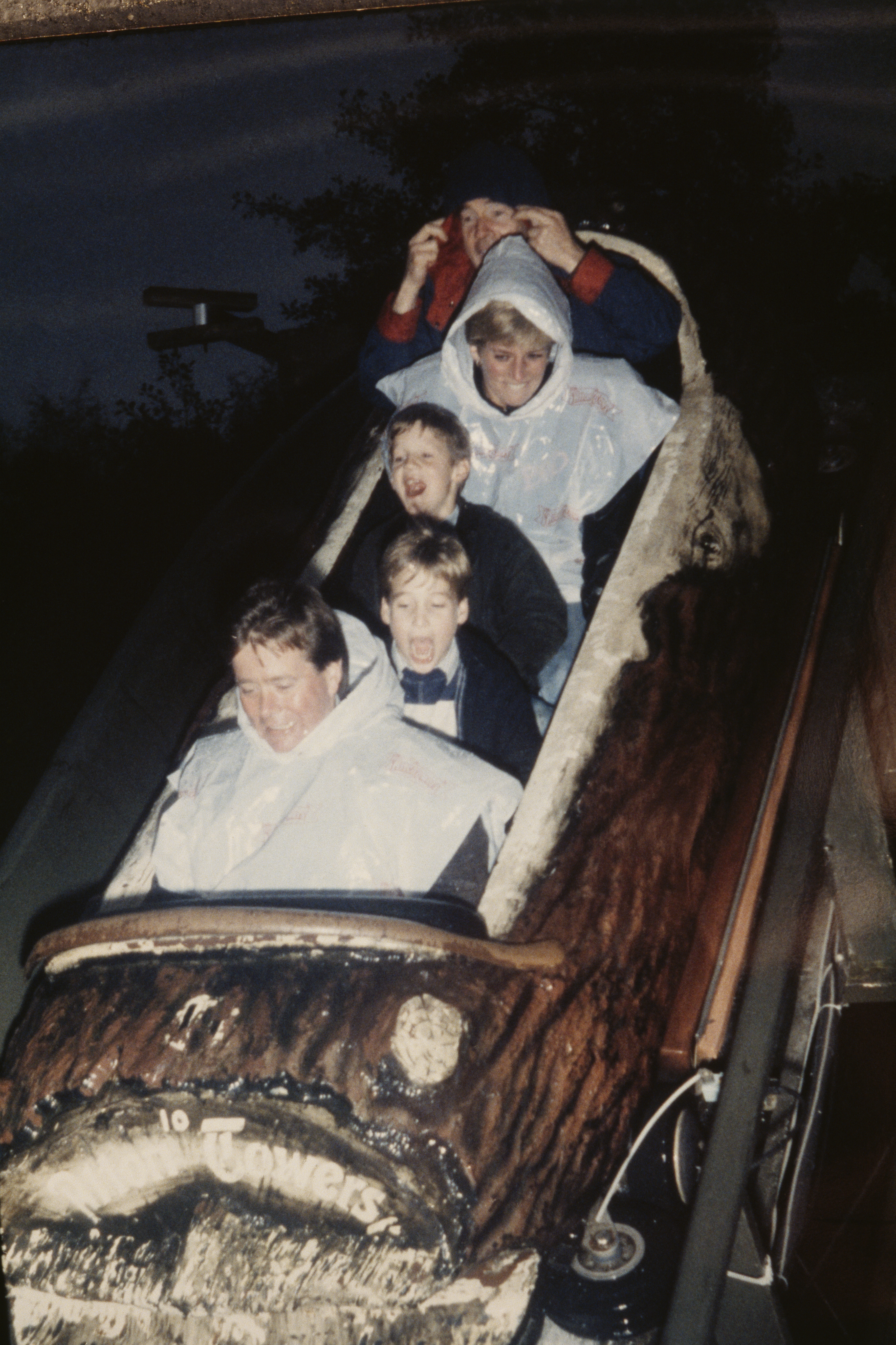 Princess Diana rides a log flume in an amusement park with sons Prince William and Prince Harry