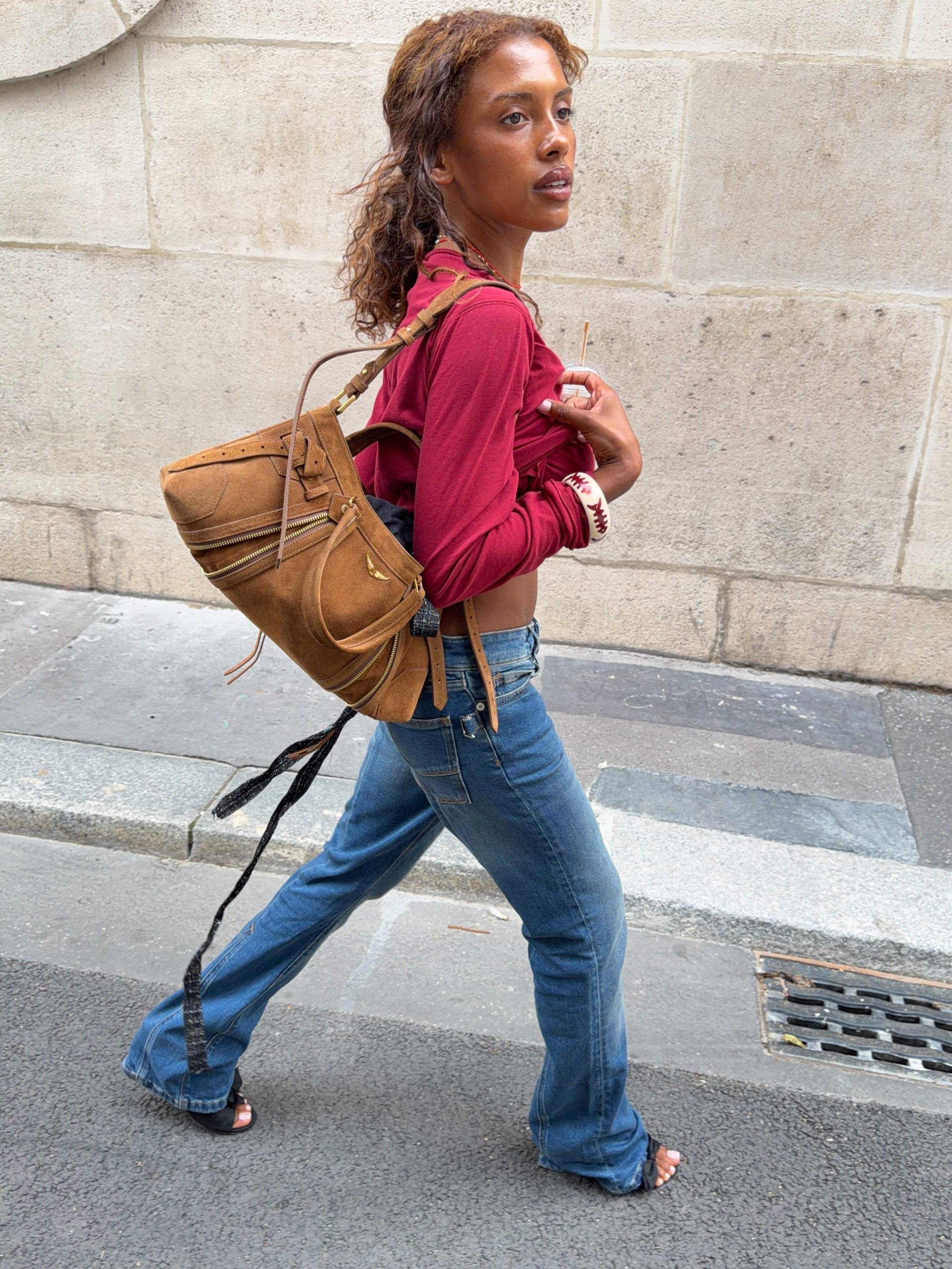 An image of @mv.tiangue wearing a cherry red shirt and blue jeans.
