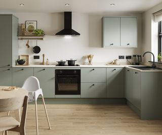 kitchen with pale green doors, white worktops and pale oak flooring