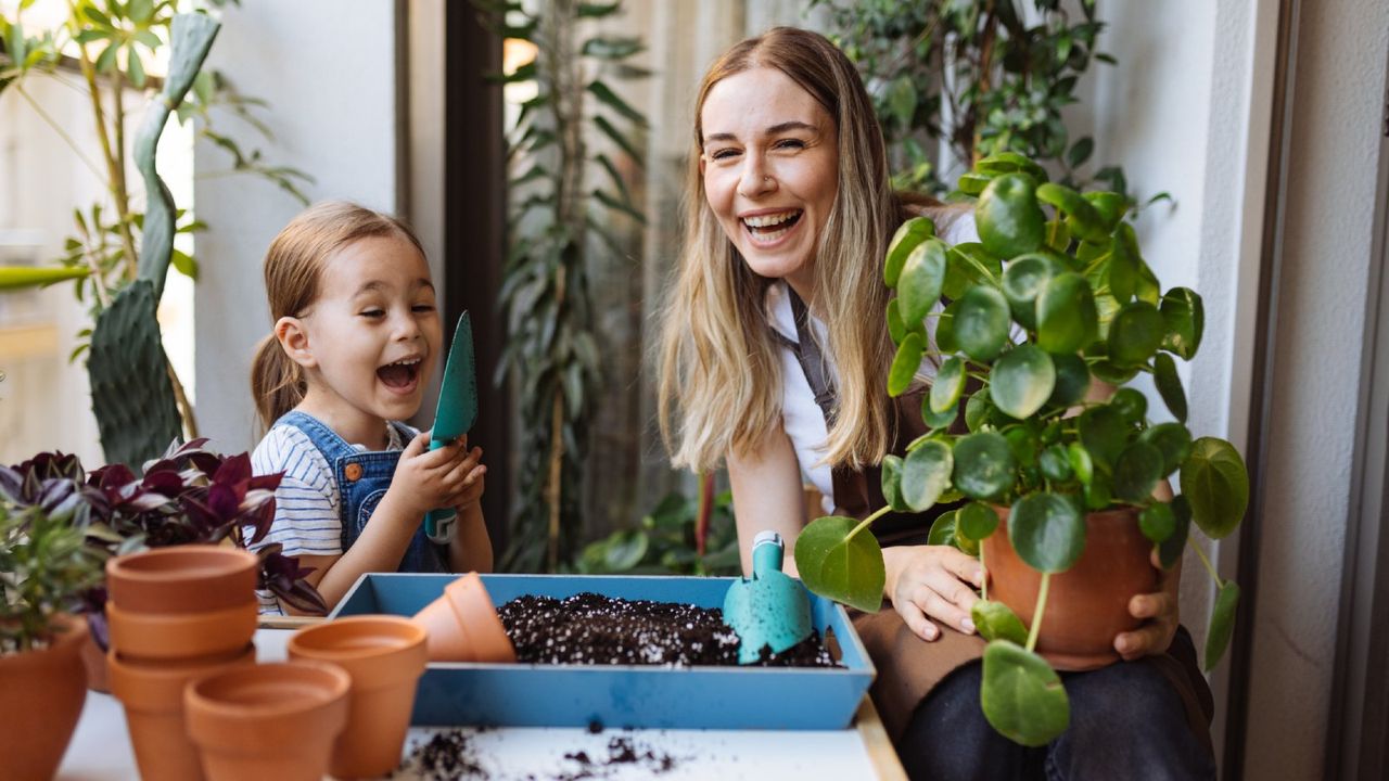 woman and child laughing holding plants