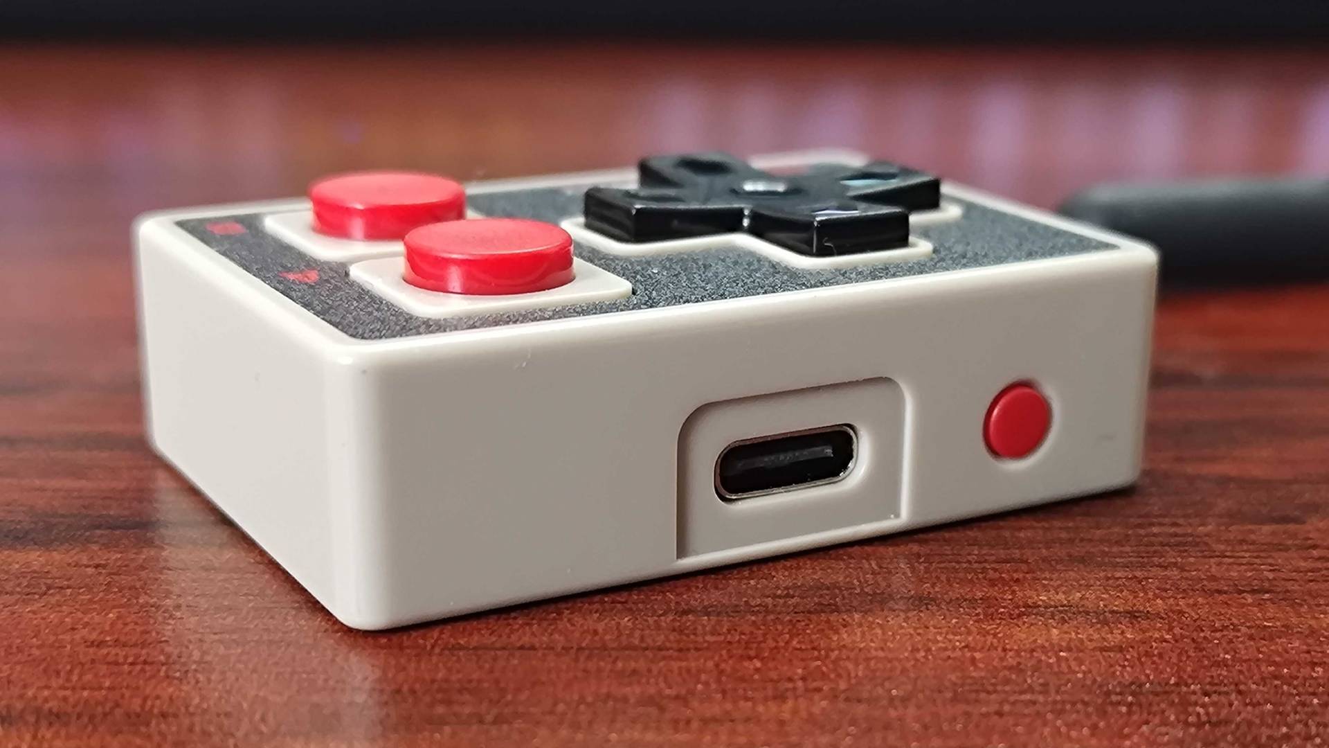 IINE Gamebrick Mini on woodgrain desk with USB-C port in view.