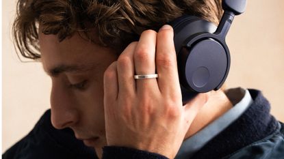 A man with dark hair wearing Cambridge Audio P100 SE headphones in their new blue colour