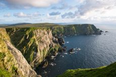 The UK coastline. The green cliffs are on the left of the image, with a blue sky and ocean.