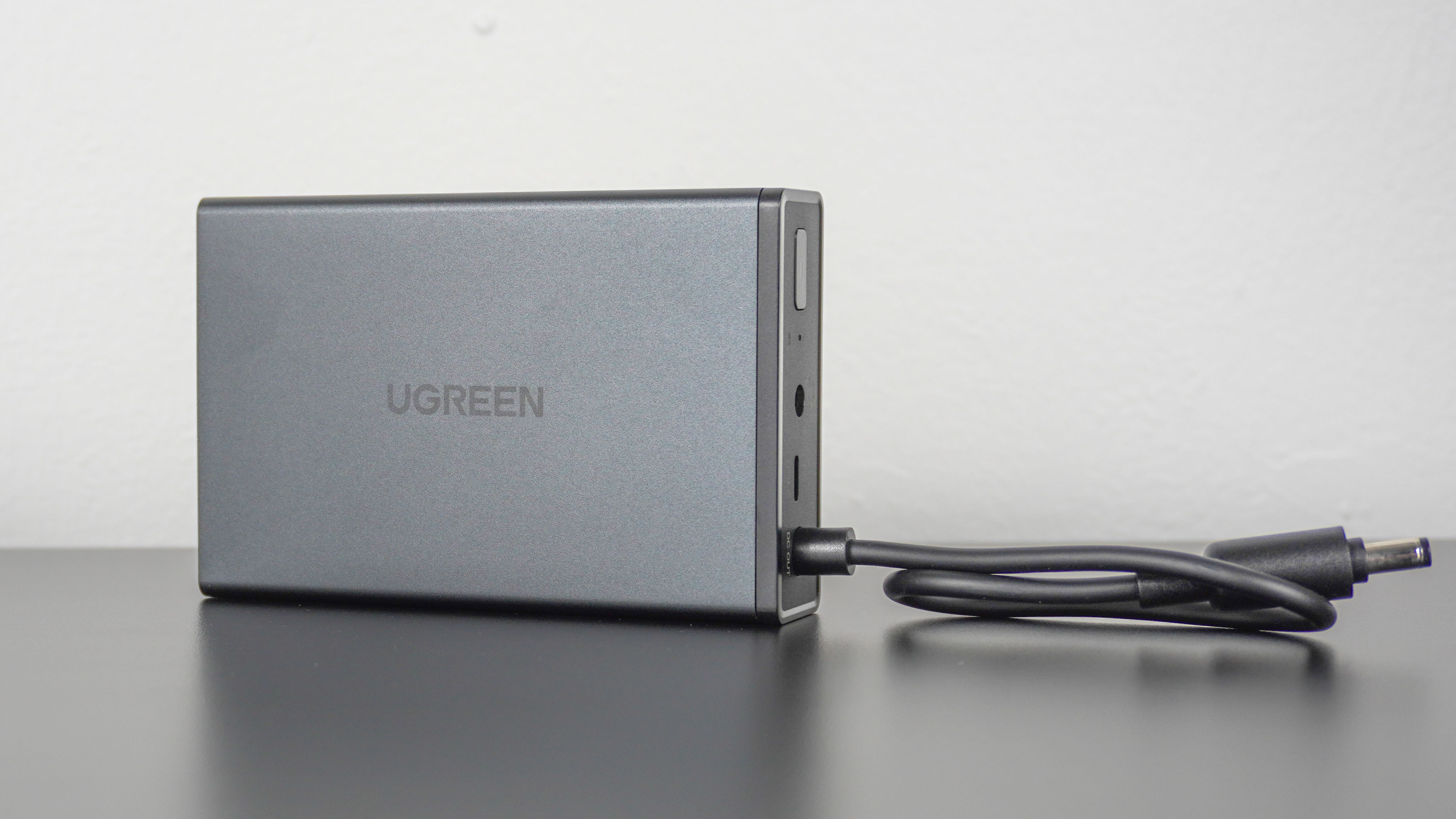 The Ugreen US3000 mini UPS seen from the side showing off its hardwired power out cable