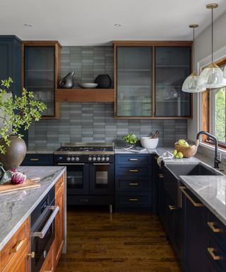 kitchen renovation rules, blue and grey kitchen with grey tiled backsplash, glazed wall cabinetry with wood finish, blue base cabinets, pale grey marble style countertops, hardwood floor, kitchen island with oven