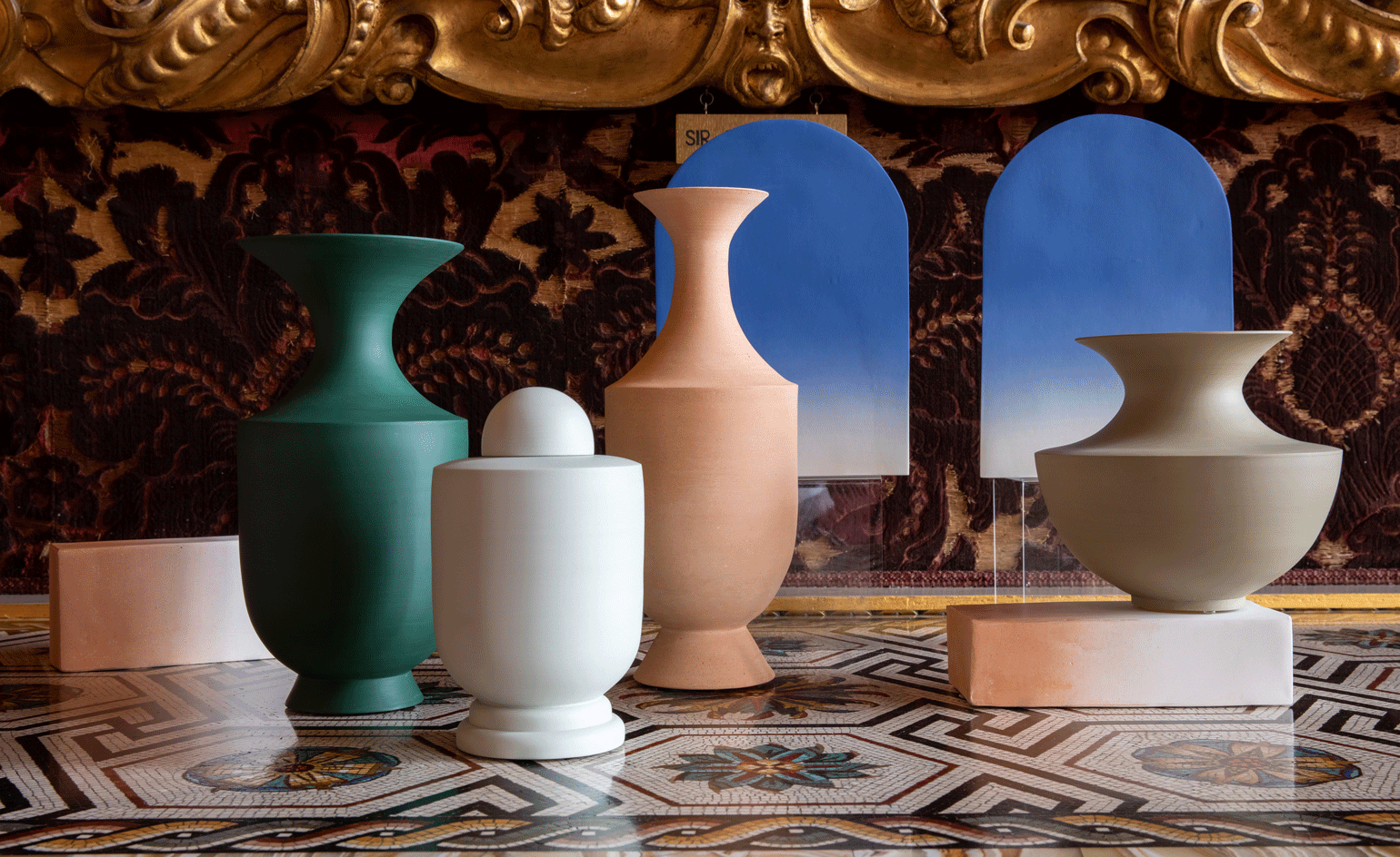 coloured cermaic vases against an ornate background