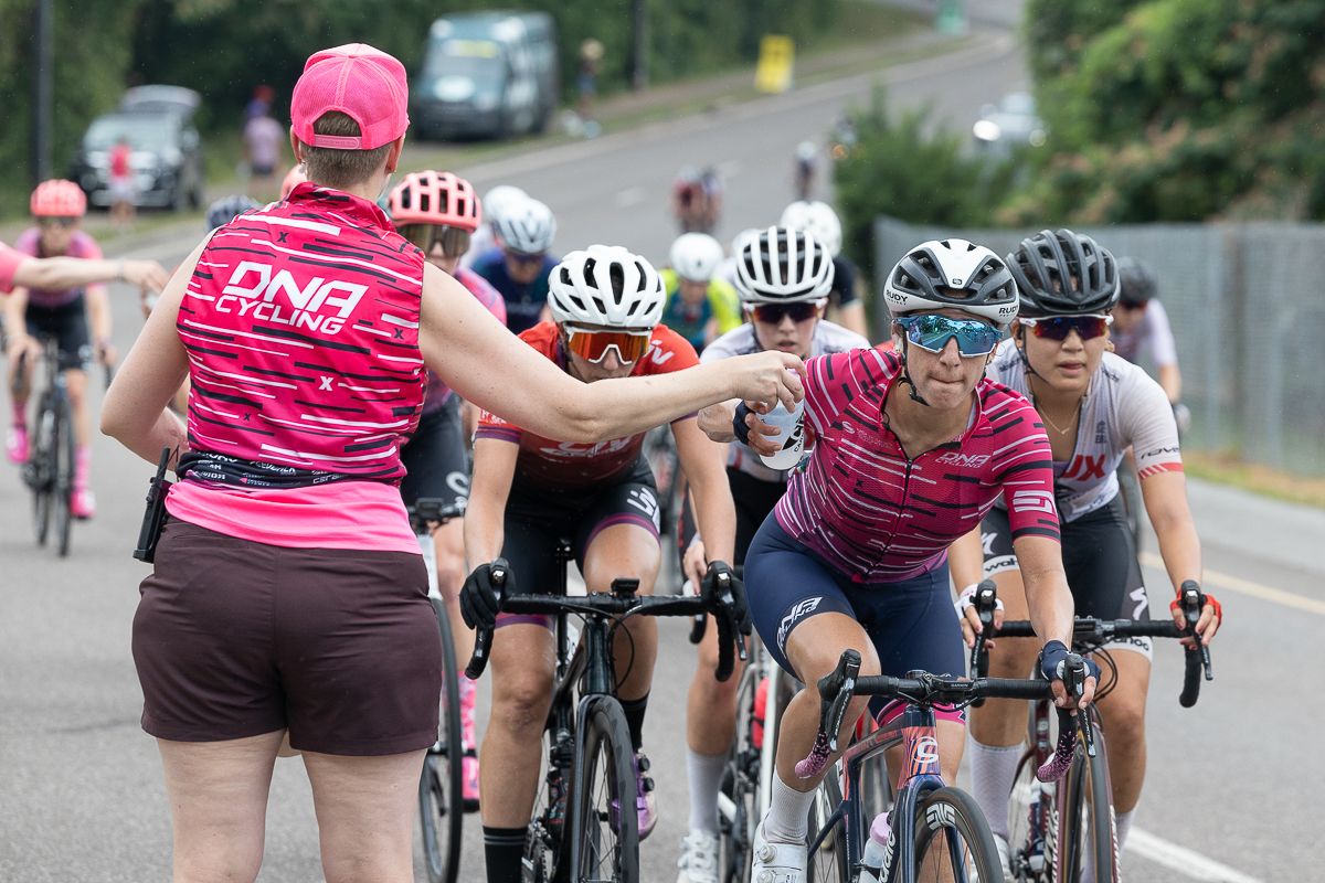 Despite being overcast and a little cooler than forecasted, the feed zone was busy for both races. Here Erica Clevenger (DNA Pro Cycling) takes on a bottle.