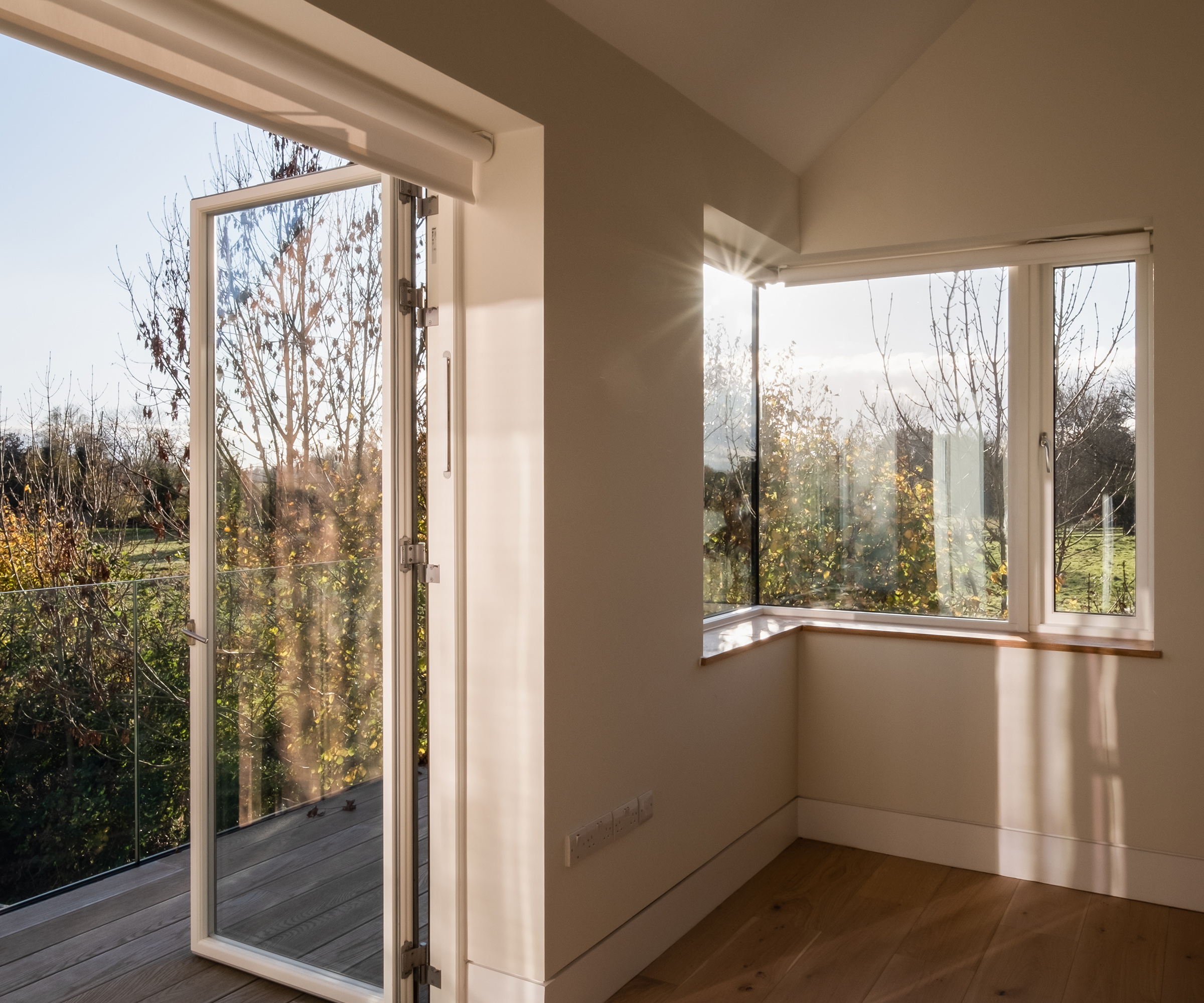A room of a self build home filled natural light and doors opening out onto a small wooden balcony terrace