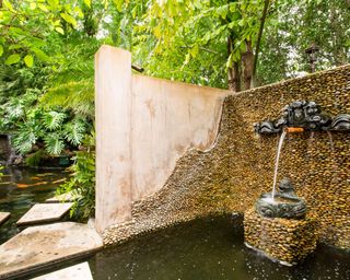 Backyard landscaping ideas showing a fish pond surrounded by a stone wall