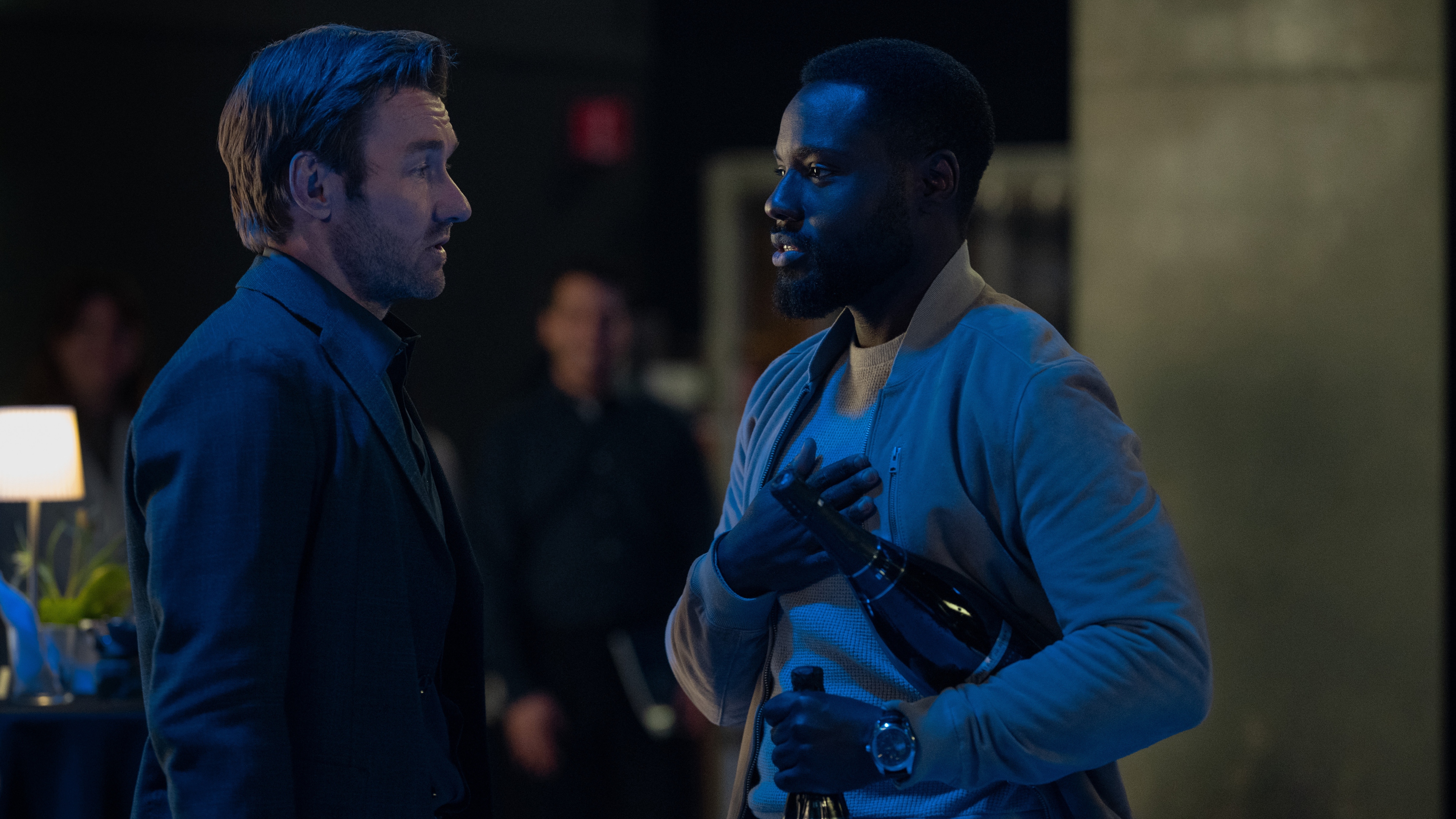 Jason Dessen (Joel Edgerton) and Leighton Vance (Dayo Okeniyi) holding a bottle of champagne under his arm in Dark Matter season 2.