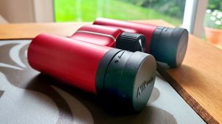 Nikon Aculon T02 8x21 binoculars on a wooden table by a window