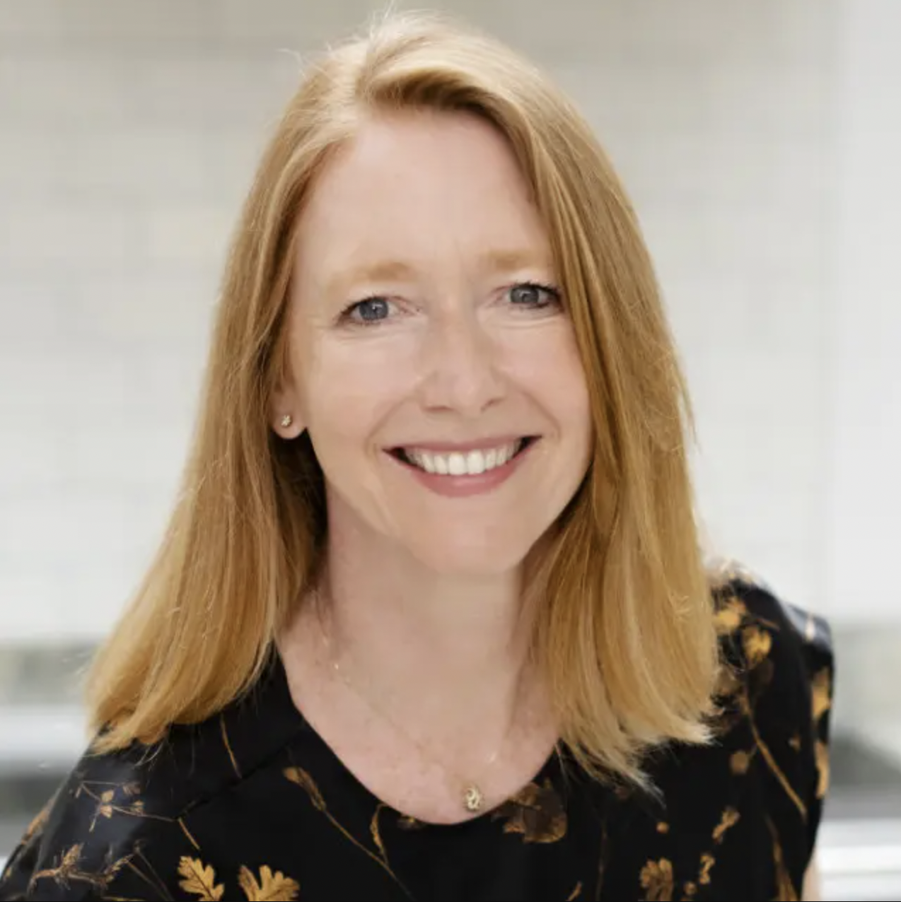 A headshot of a woman with red hair smiling at the camera