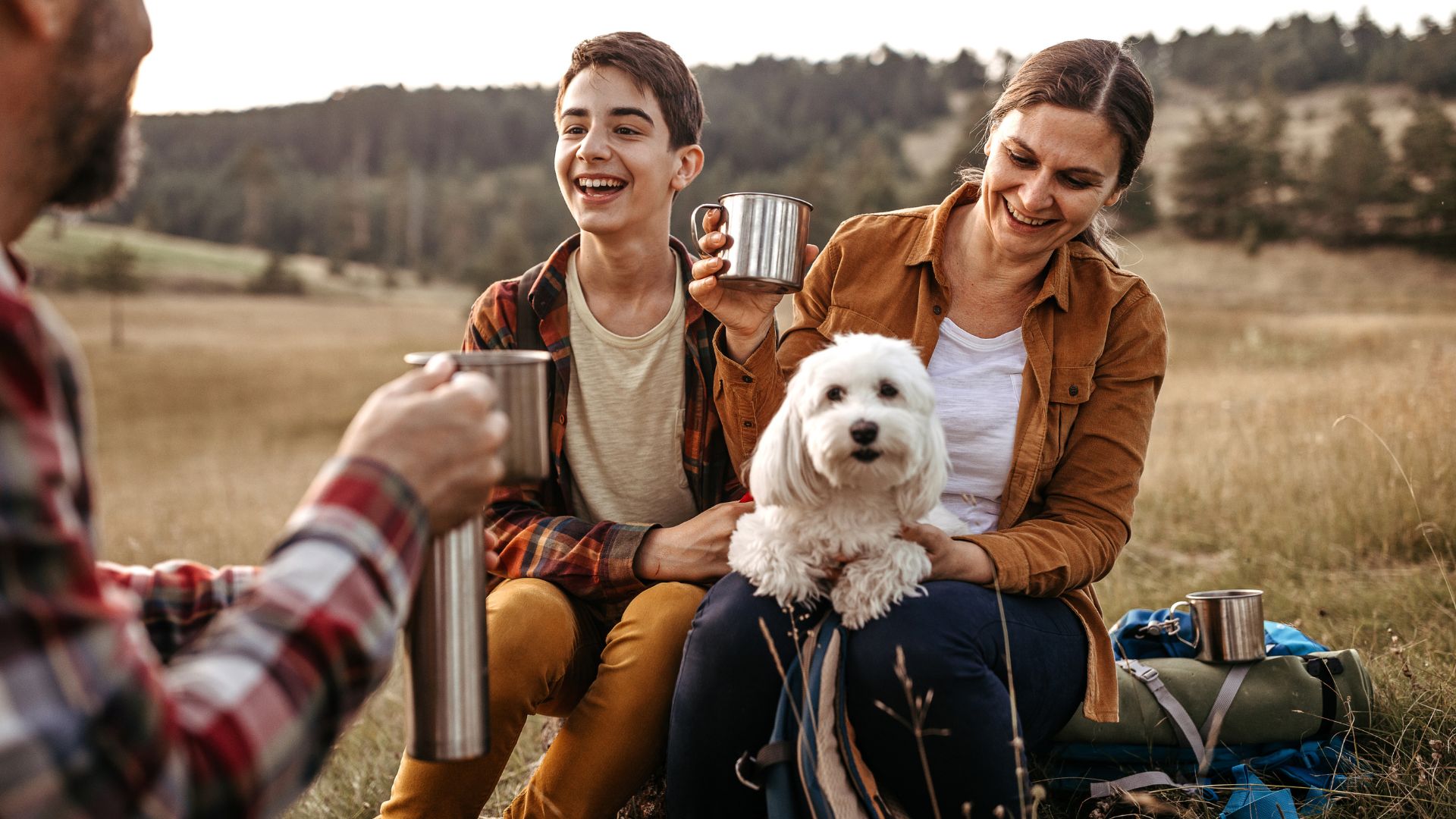 Three people drinking tea with white dog on lap