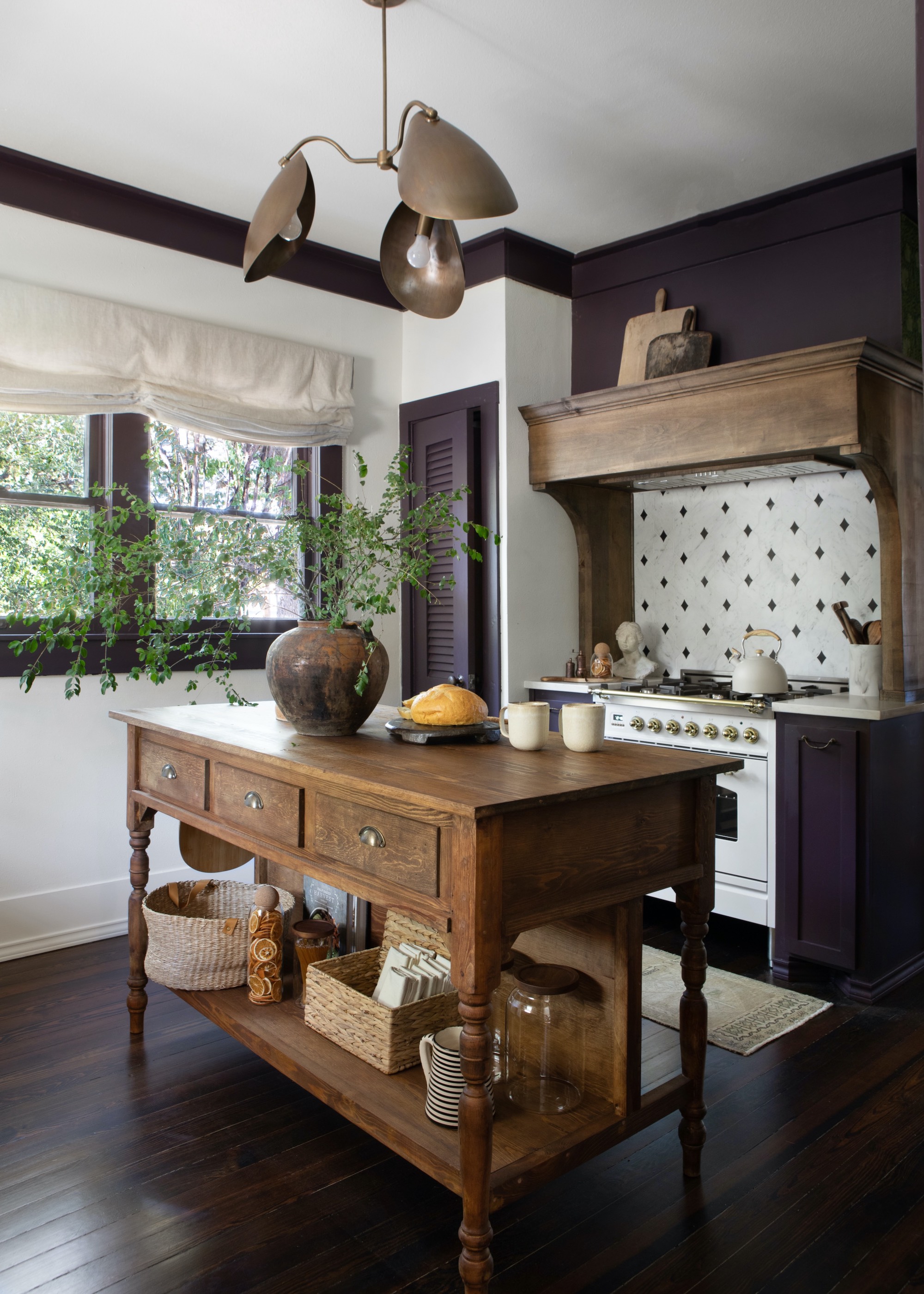 kitchen with vintage island in the middle that has drawers and extra storage space. On the island is a vase with a plant on top.