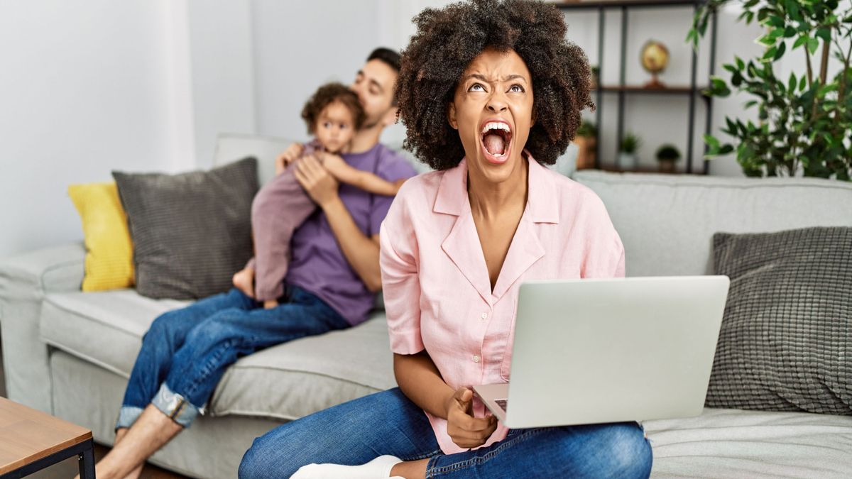 Angry mum working on a laptop at home