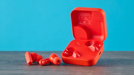 cmf buds 2a in the orange colorway photographed in front of a blue background