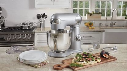 A silver Cuisinart stand mixer in an elegant country kitchen, next to a board of fig flat breads