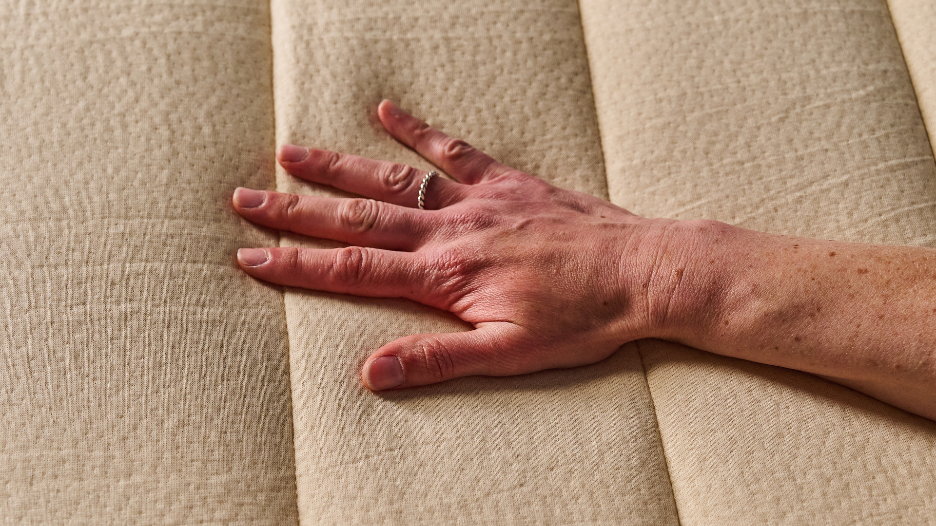 A Tom's Guide tester's hand feeling the cool surface of the Birch Luxe Natural mattress