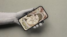 Photo collage of a woman's hand holding a phone screen with a diagram of a baby in a womb on the screen